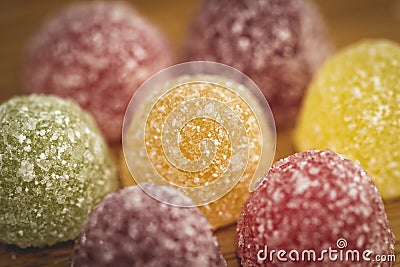 A macro portrait of a piece of colorful candy with some other sweets of the same kind around it. Stock Photo