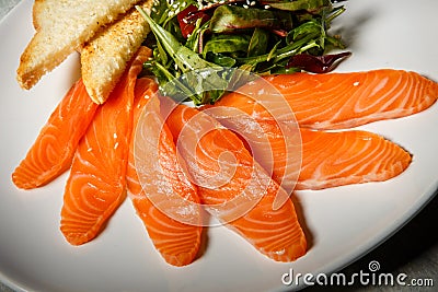 macro salmon slices served with rucola and tomato salad and toasted bread Stock Photo