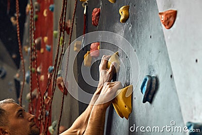 Macro shot of climbers hands gripping colourful handholds during indoor workout Stock Photo