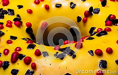 Macro shot of donut or doughnut with yellow frosting covered by black and red sprinkles topping Stock Photo