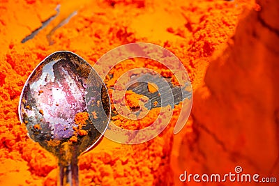 Macro shot of a spoon in a pile of orange pigment in the city of Pushkar Stock Photo