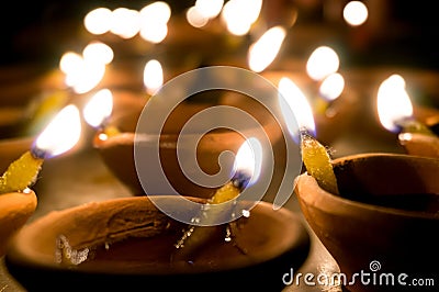 Macro shots of diyas being lit by hand or candle for the hindu religious festival of Diwali. Stock Photo