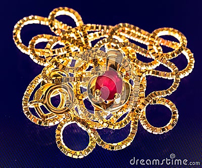 Macrophoto of a lovely golden necklace with a ruby stone in polarized light Stock Photo