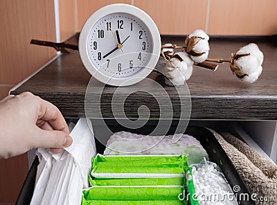 Sanitary napkin, tampon and cotton plant flower. Women hands pull out drawer containing hygiene products to help with menstruation Stock Photo