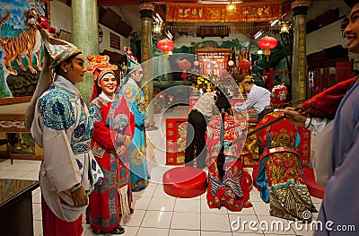 Made-up actores of Chinese opera in vintage costumes praying inside colorful Buddhist temple in old style Editorial Stock Photo