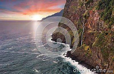 Madeira island - Dramatic sunrise over atlantic ocean with waterfall landscape from Miradouro do Veu da Noiva Stock Photo