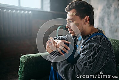 Madman in uniform with plasters on face and hands Stock Photo