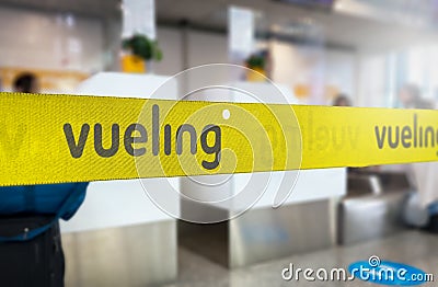 Yellow retractable belt barrier with grey Vueling airlines logo Editorial Stock Photo