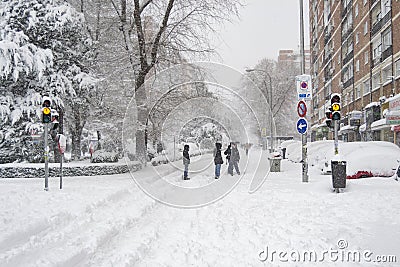 MADRID, SPAIN - JANUARY 9, 2021. Sheltered people walking on the snow-filled road. Editorial Stock Photo