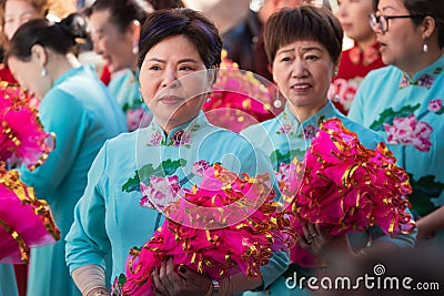 Women Participants in the Chinese New Year parade dressed in traditional light blue costume and carrying fans. In the neighborhood Editorial Stock Photo