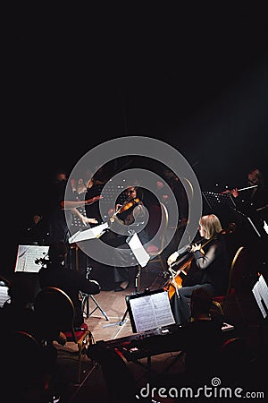 Symphony orchestra concert in mysterious darkness under stage spotlights. The conductor controls Editorial Stock Photo