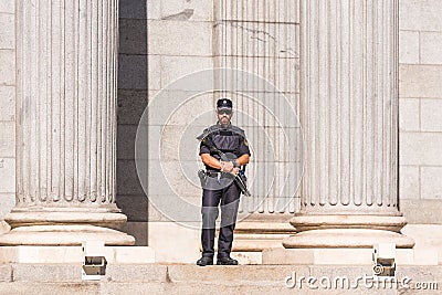 MADRID, SPAIN - SEPTEMBER 26, 2017: A policeman armed with a shotgun and body armor stands guard in front of the Congress of Deput Editorial Stock Photo
