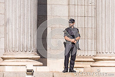 MADRID, SPAIN - SEPTEMBER 26, 2017: A policeman armed with a shotgun and body armor stands guard in front of the Congress of Deput Editorial Stock Photo