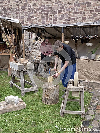 Magdeburg, Germany - 29.08.2014: Kaiser-Otto-Fest. Reconstruction of historical events of the city Magdeburg. Young man chops wood Editorial Stock Photo