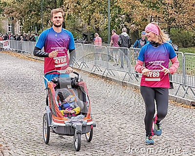 A young family with baby in a stroller is running a marathon. Active and healthy lifestyle. Leisure sports activities for people Editorial Stock Photo