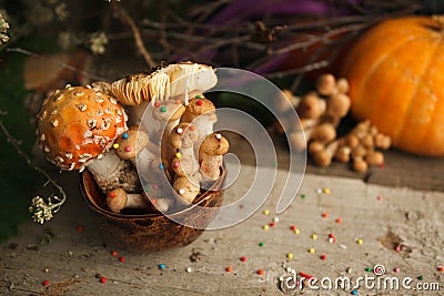 Magic fairytale party table decor, mushroom with confectionary in cup on wooden background, poison toxic food, halloween holiday. Stock Photo