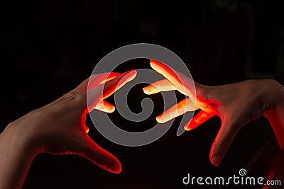 Magic hands cast spells at each other, silhouetted in a reddish glow Stock Photo