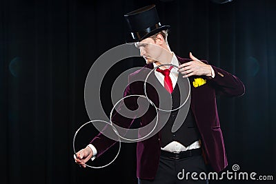 Magic, performance, circus, show concept - magician in top hat showing trick with linking rings Stock Photo