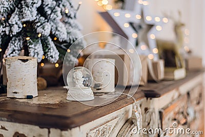 Magical Christmas snow globe with little angel statue inside. Christmas decoration around. Shallow depth of field with Stock Photo