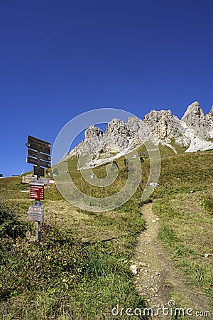 Magical Dolomite peaks of Pizes da Cir, Passo Gardena at blue sky and sunny day with a hiking trail direction signpost, South Editorial Stock Photo