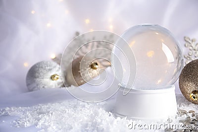 Magical empty snow globe with Christmas decorations on white fabric. Stock Photo