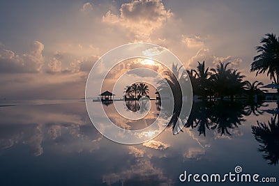 Magical golden sunset with clouds on a beach in Maldives, reflected in an infinity pool Stock Photo