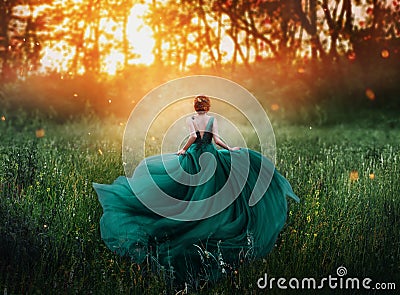 Magical picture, girl with red hair runs into dark mysterious forest, lady in long elegant royal expensive emerald green Stock Photo