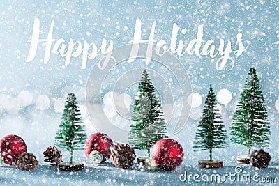 Magical snowy miniature winter wonderland background. Evergreen trees, pine cones and red christmas baubles on shiny background. Stock Photo