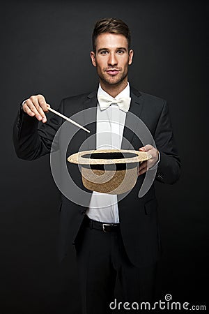 A magician in a black suit holding an empty top hat Stock Photo