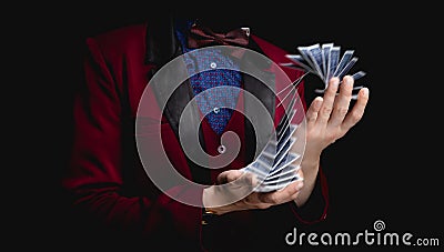 Magician shows trick with playing cards on dark background, concept stand-up Stock Photo