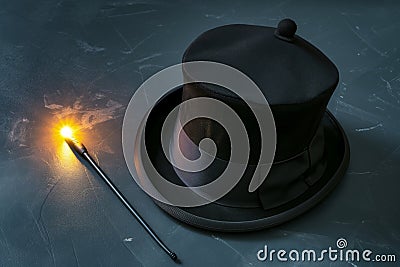 magicians hat lying on its side, wand with a glowing tip nearby Stock Photo