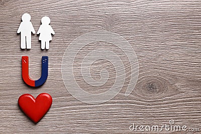 Magnet attracting paper couple on wooden background, flat lay with space for text. Love concept Stock Photo