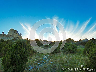 Magnificent blue sky embellished with frayed white clouds which embellish the landscape with the castle of Queen Jeanne next to it Stock Photo