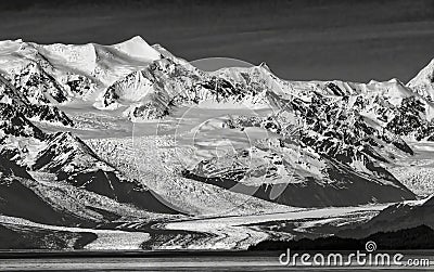Bright snow and a dramatic glacier flows down to the water in monochrome image Stock Photo