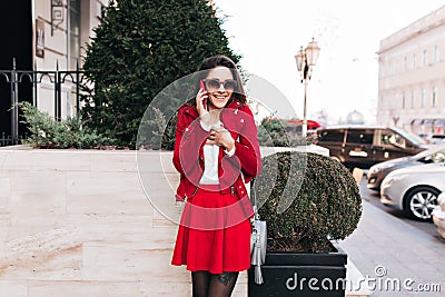 Magnificent slim girl in pantyhose talking on phone in warm morning. Outdoor photo of european young woman in short Stock Photo