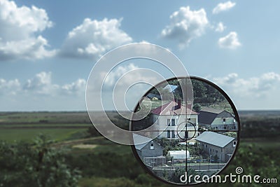 A magnified view of a house in the valley in a sniper`s optical sight. Killer looks into the optical sight Stock Photo