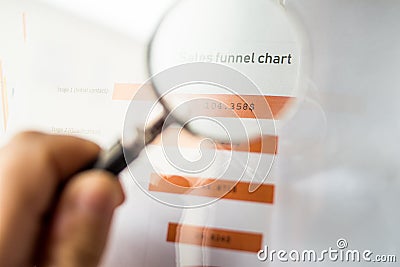 Magnifier on a coloured funnel chart printed on a white sheet of paper during a business meeting Stock Photo