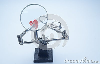 Magnifier with forceps holds scissors and applique hearts Stock Photo