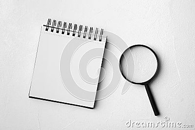 Magnifier glass and empty notebook on stone background, flat lay with space for text. Find keywords concept Stock Photo