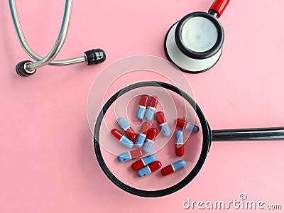Magnifier with medical pills and red stethoscope closeup Stock Photo