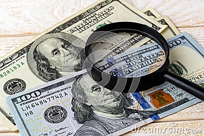 Magnifier on new and old dollar banknotes on a white wooden surface. Check the authenticity of money. Wealth, poverty and Stock Photo