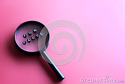 Magnifying glass and alphabet beads with text FUN FACTS Stock Photo