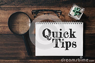 Magnifying glass, glasses, cactus and notebook with QUICK TIPS word on wooden table Stock Photo