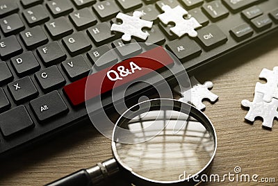 Magnifying glass, jigsaw puzzle and computer keyboard with red button written with QNA or Questions and Answers Stock Photo