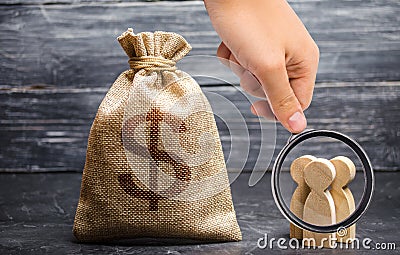 Magnifying glass is looking at the people figurines and a money bag with a dollar sign. concept of attracting investment, business Stock Photo