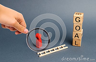 Magnifying glass is looking at a red figure of a man stands near fallen ladder and a tower of cubes with an inscription goal Stock Photo