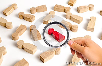 Magnifying glass is looking at the red human figure among many other people. Employee search concept, recruitment and personnel Stock Photo