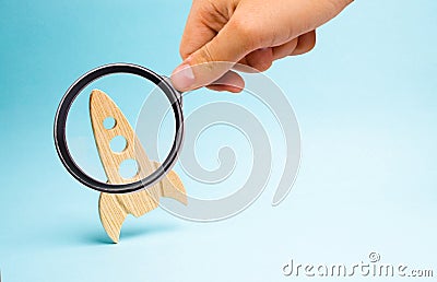 Magnifying glass is looking at the Rocket on a blue background. concept of a startup, education and the desire to research. Space Stock Photo