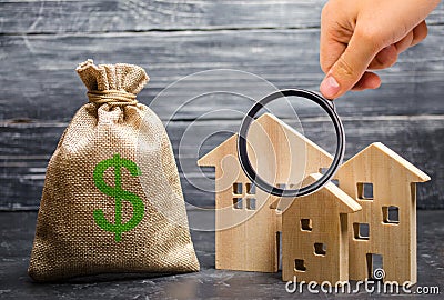 Magnifying glass is looking at the three houses near a bag with money. real estate acquisition and investment. Stock Photo