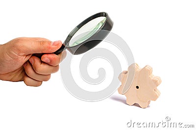 Magnifying glass is looking at the Wooden gear on a white background. The concept of technology and industry, the think process. Stock Photo